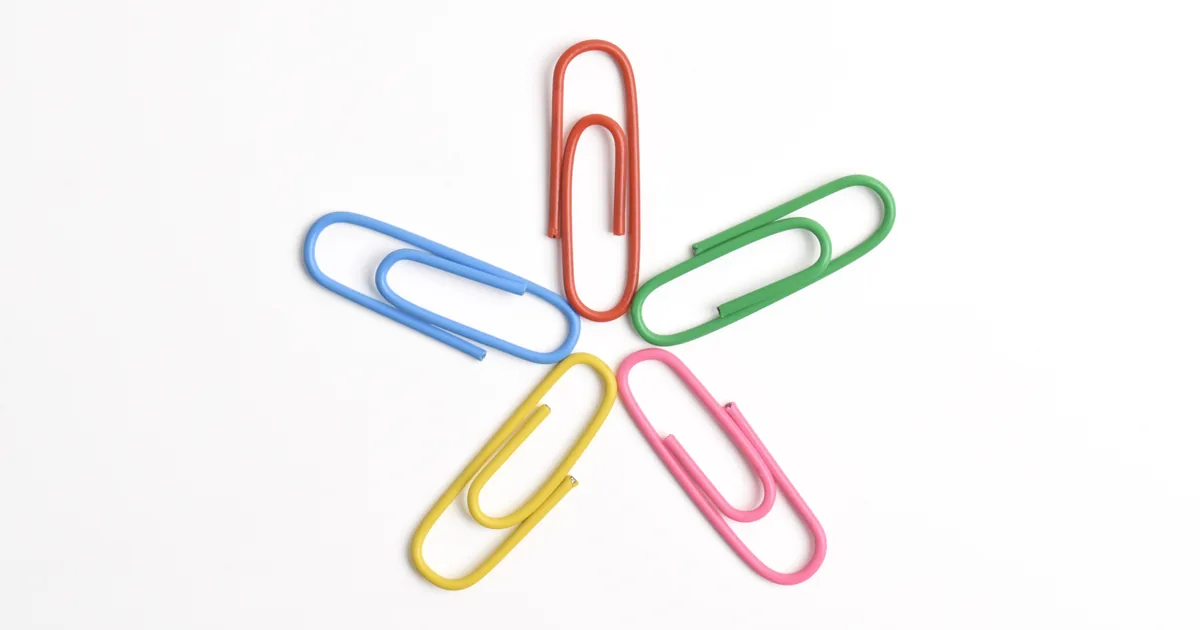 Five colored paperclips arranged in a star on a white background, like separate AI agents linked into one team.